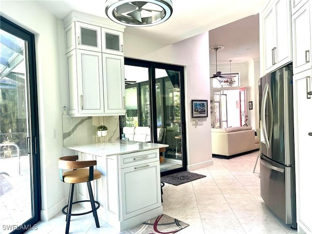 kitchen with a breakfast bar, white cabinets, light countertops, and freestanding refrigerator