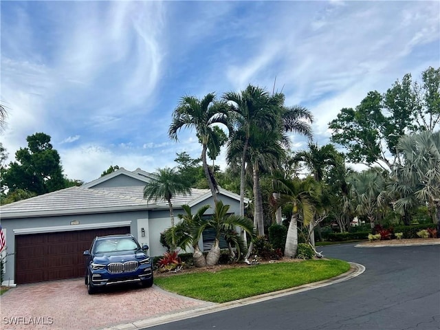 view of front facade featuring decorative driveway, an attached garage, and stucco siding