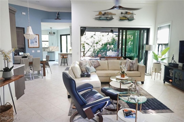 living area featuring ceiling fan, plenty of natural light, ornamental molding, and light tile patterned flooring