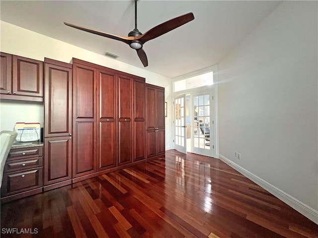 unfurnished bedroom with a ceiling fan, dark wood-style floors, visible vents, and baseboards