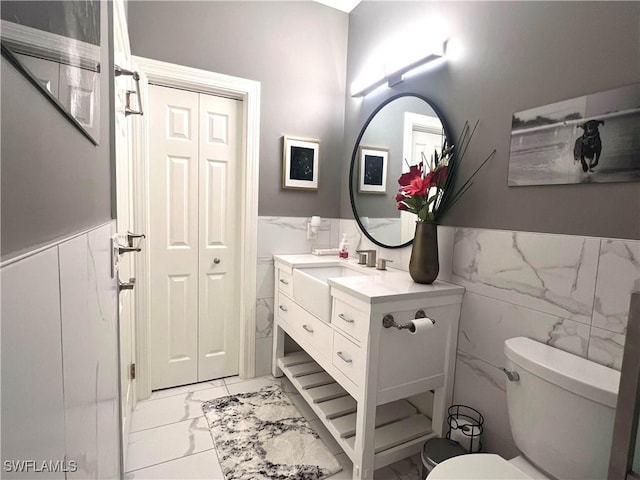 bathroom with toilet, marble finish floor, a closet, wainscoting, and vanity