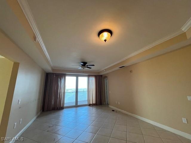 spare room with a ceiling fan, crown molding, and baseboards