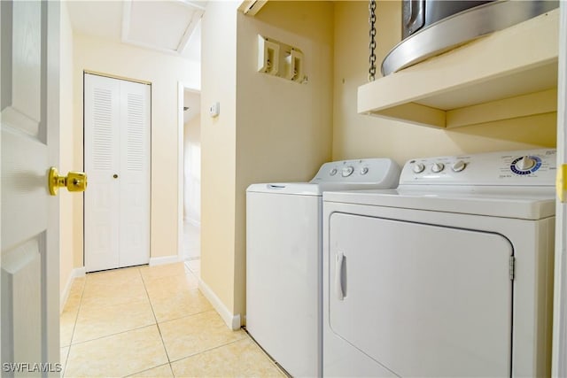 laundry area featuring washer and clothes dryer, light tile patterned floors, laundry area, and baseboards