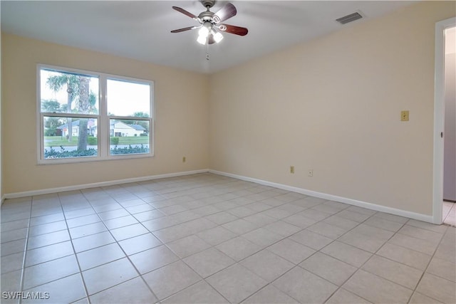 empty room featuring light tile patterned floors, visible vents, baseboards, and a ceiling fan