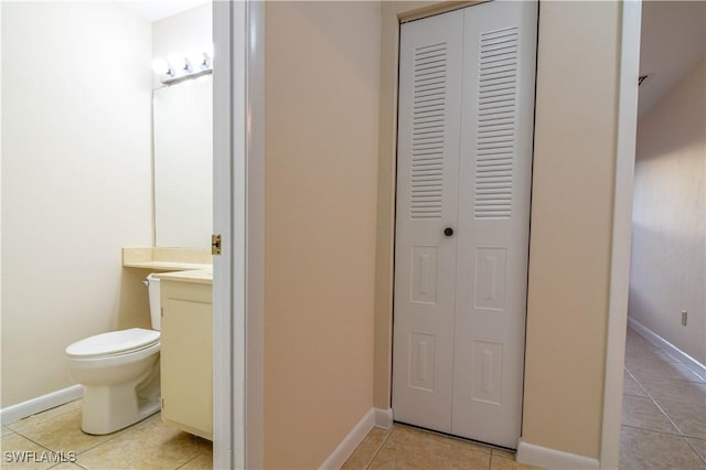 bathroom with tile patterned floors, toilet, vanity, and a closet