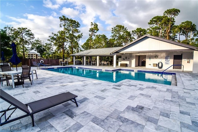 community pool with a patio area and fence