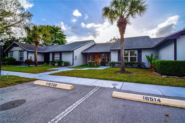 ranch-style home with uncovered parking and a front yard