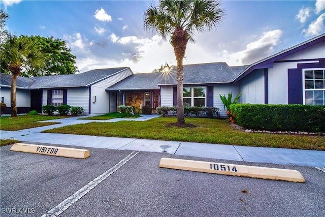 single story home featuring uncovered parking and a front lawn