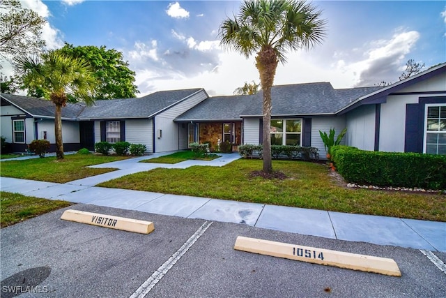 ranch-style home with uncovered parking and a front lawn