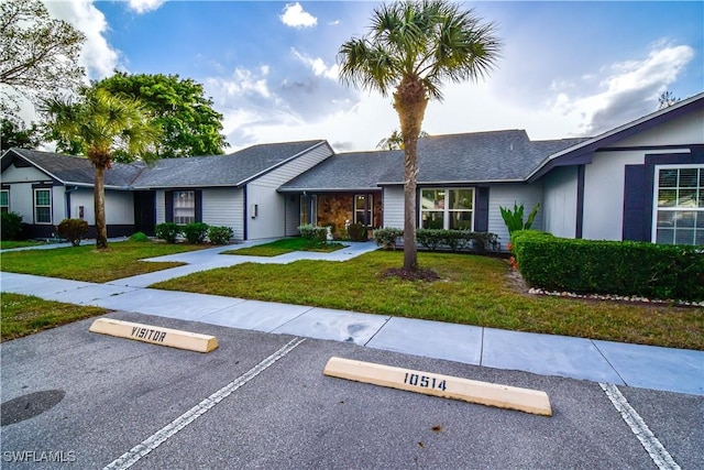 ranch-style house with a front lawn and uncovered parking