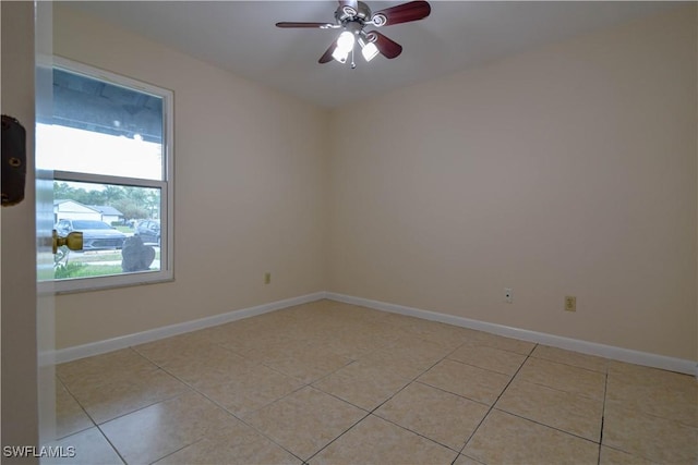 empty room featuring light tile patterned floors, baseboards, and a ceiling fan