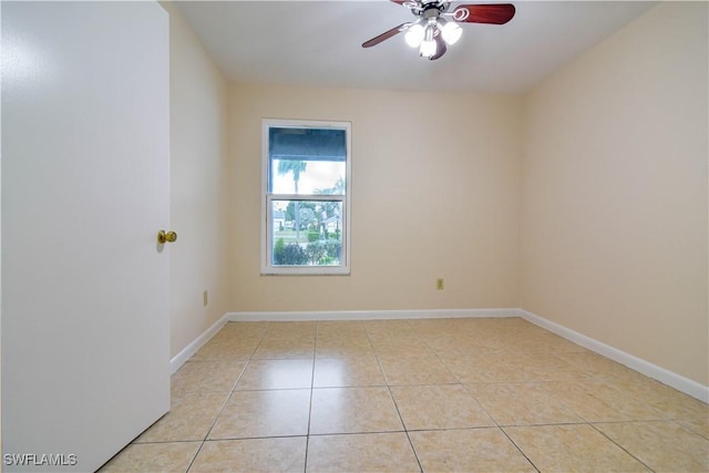 empty room featuring light tile patterned flooring, baseboards, and a ceiling fan