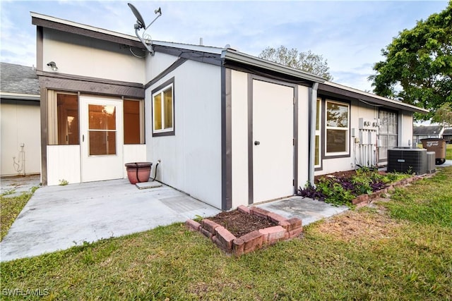 rear view of house featuring a patio area, a lawn, and central AC