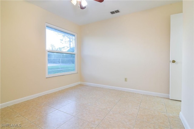 empty room featuring light tile patterned flooring, visible vents, baseboards, and ceiling fan