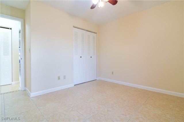 unfurnished bedroom with light tile patterned flooring, a closet, baseboards, and a ceiling fan