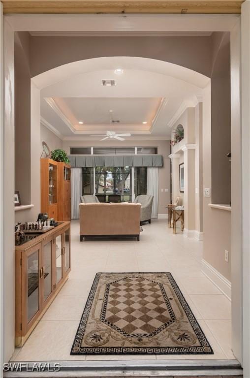 interior space with visible vents, ornamental molding, arched walkways, light tile patterned floors, and a raised ceiling