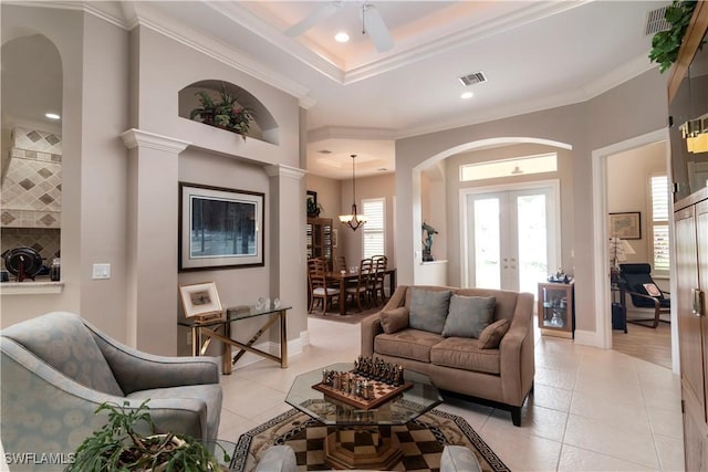 living room with crown molding, light tile patterned floors, visible vents, and arched walkways