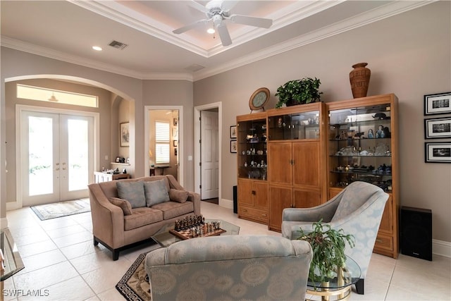 living room featuring light tile patterned floors, visible vents, arched walkways, and crown molding