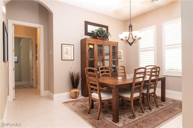 dining space featuring light tile patterned flooring, baseboards, arched walkways, and a chandelier