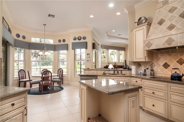 kitchen featuring visible vents, a sink, decorative backsplash, cream cabinetry, and crown molding