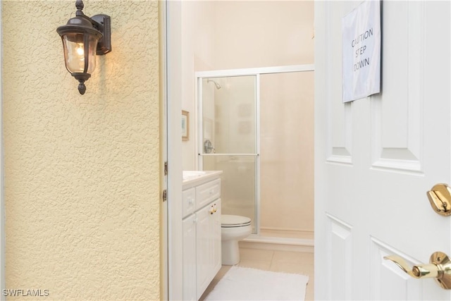 bathroom with tile patterned flooring, toilet, vanity, and a stall shower