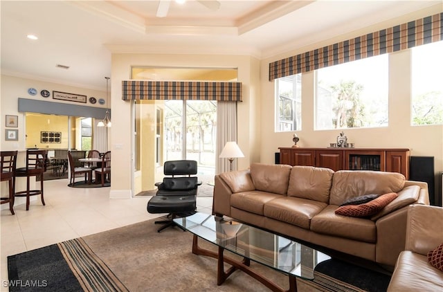 living area with visible vents, a ceiling fan, a tray ceiling, light tile patterned flooring, and crown molding