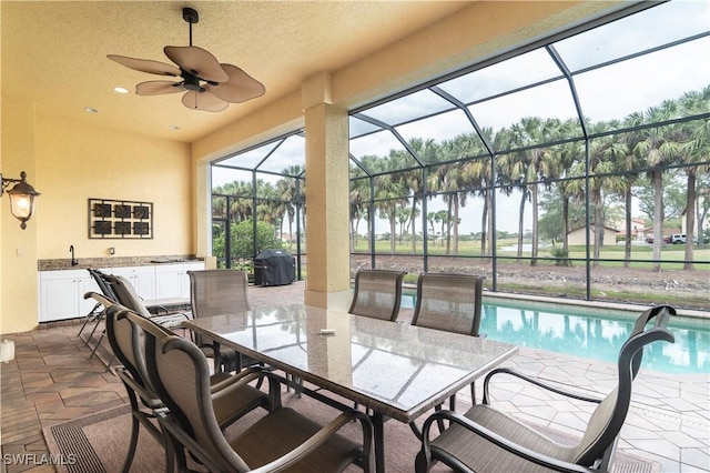 exterior space featuring glass enclosure, a grill, outdoor dining area, an outdoor pool, and a sink