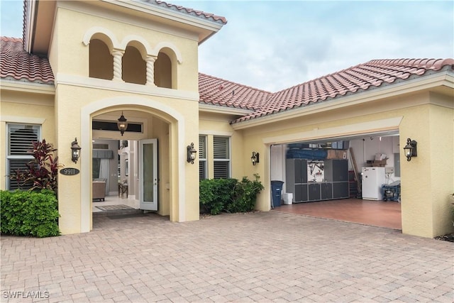 exterior space featuring a tile roof, decorative driveway, a garage, and stucco siding