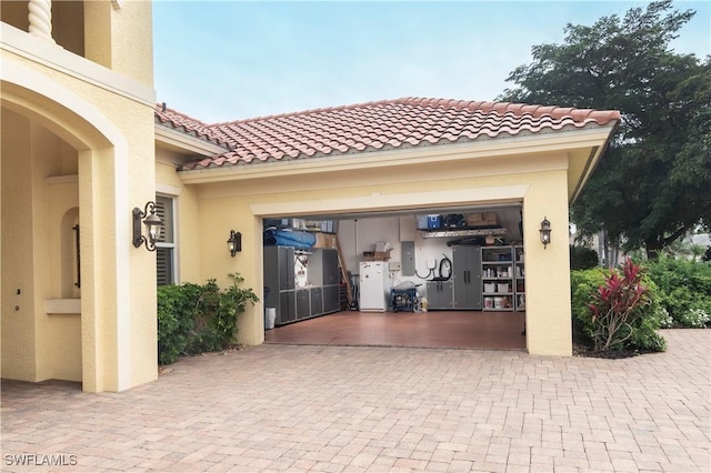 garage with freestanding refrigerator and decorative driveway