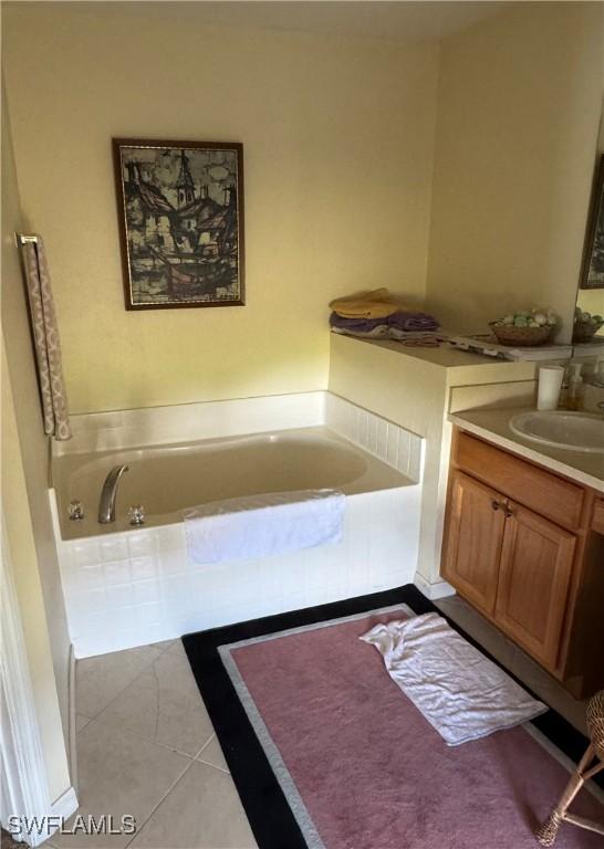 bathroom with tile patterned floors, a garden tub, and vanity