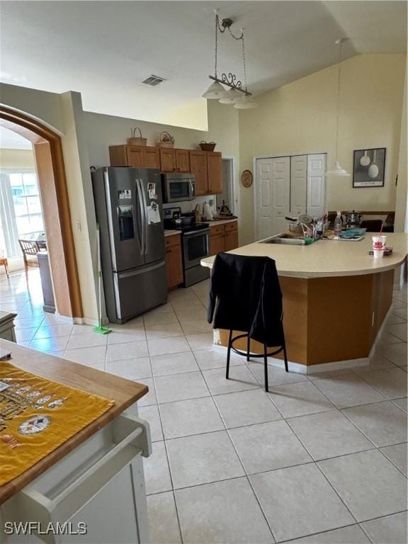 kitchen with light tile patterned floors, visible vents, arched walkways, vaulted ceiling, and appliances with stainless steel finishes