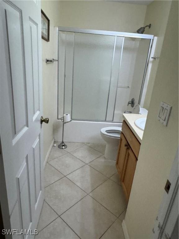 bathroom with tile patterned flooring, combined bath / shower with glass door, toilet, and vanity