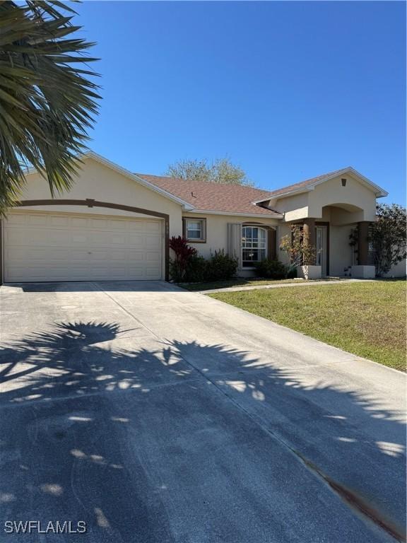 view of front of home with stucco siding, driveway, a front yard, and a garage