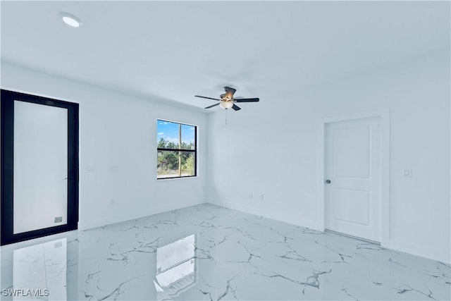 spare room featuring a ceiling fan, baseboards, and marble finish floor