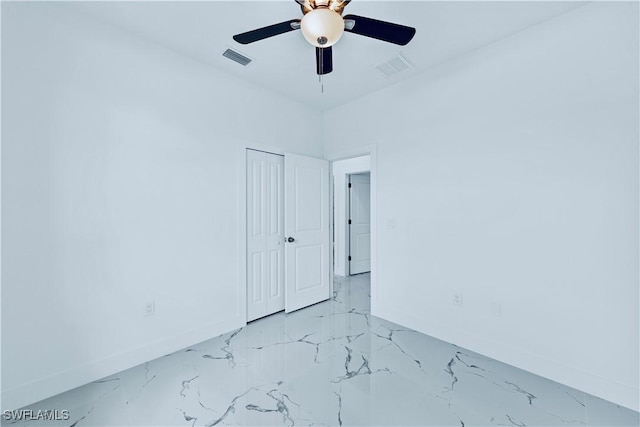 spare room featuring a ceiling fan, visible vents, marble finish floor, and baseboards