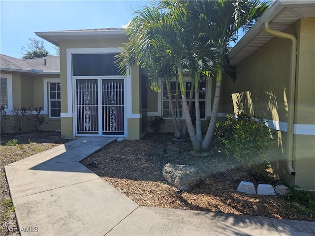 entrance to property featuring roof with shingles and stucco siding