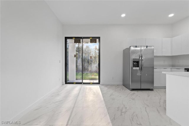 kitchen with baseboards, light countertops, white cabinets, stainless steel refrigerator with ice dispenser, and marble finish floor