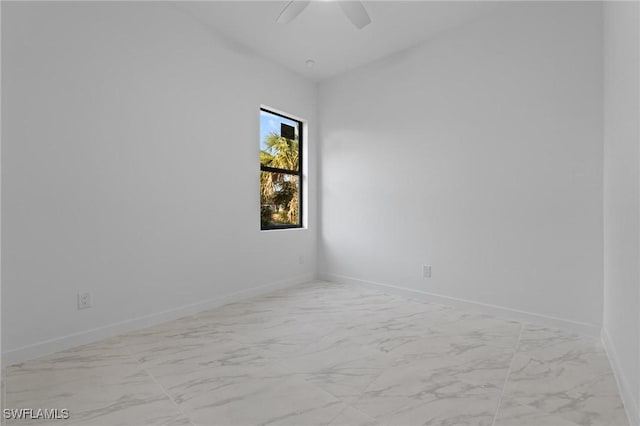 empty room featuring a ceiling fan, baseboards, and marble finish floor