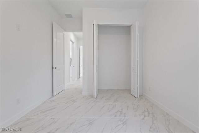 unfurnished bedroom with visible vents, baseboards, marble finish floor, and a closet