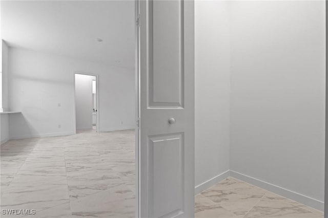 hallway with baseboards and marble finish floor