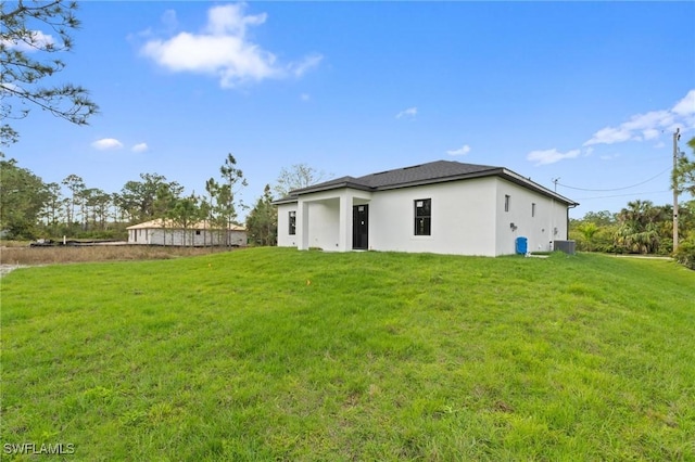 rear view of property featuring central air condition unit, a lawn, and stucco siding