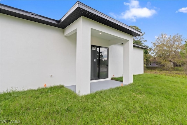 rear view of property featuring stucco siding and a lawn