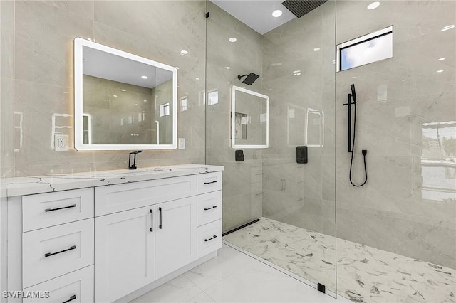 full bath with vanity, tile walls, marble finish floor, and tiled shower