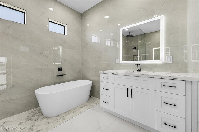 full bathroom with a freestanding tub, vanity, marble finish floor, and a shower stall