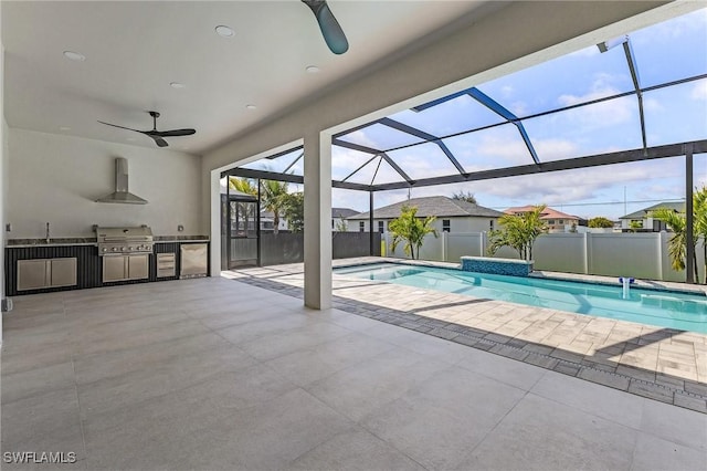 view of swimming pool with area for grilling, a sink, a patio, exterior kitchen, and a lanai