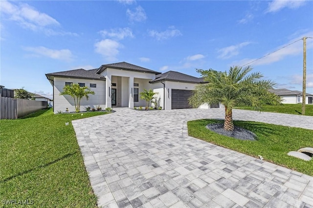 prairie-style home with stucco siding, a front lawn, decorative driveway, fence, and a garage