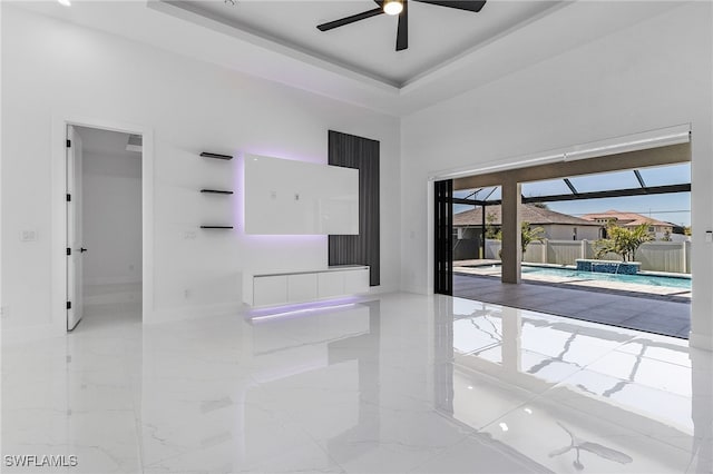 spare room featuring baseboards, a high ceiling, marble finish floor, a raised ceiling, and a ceiling fan