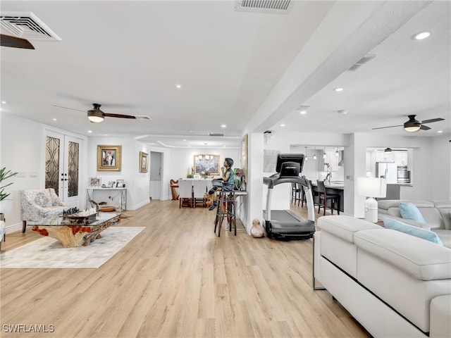 living area featuring light wood-style flooring, visible vents, and ceiling fan