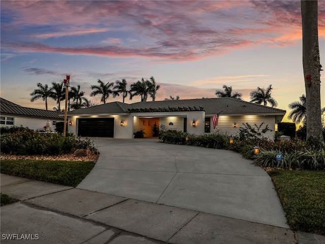 ranch-style home with a tiled roof, stucco siding, driveway, and a garage