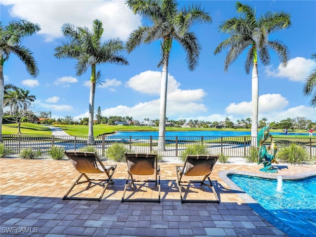 view of swimming pool featuring a water view, fence, and a patio area